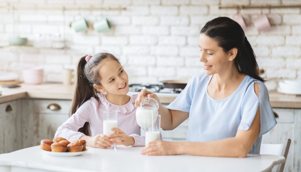 beautiful-mom-and-daughter-drinking-milk-in-kitchen-together