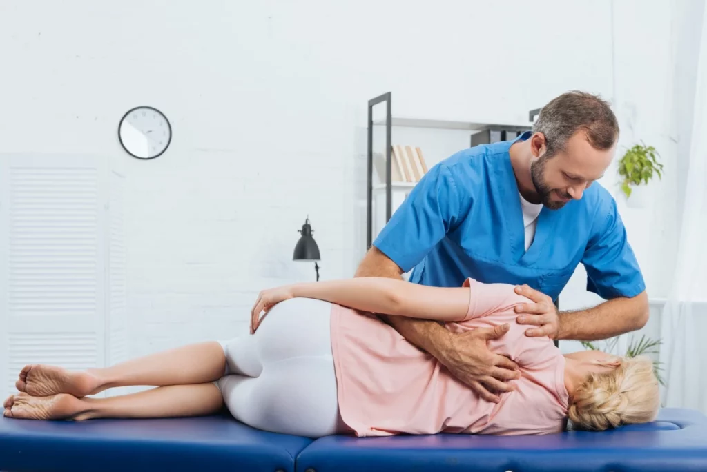 smiling-chiropractor-massaging-back-of-patient-that-lying-on-massage-table-in-hospital_1